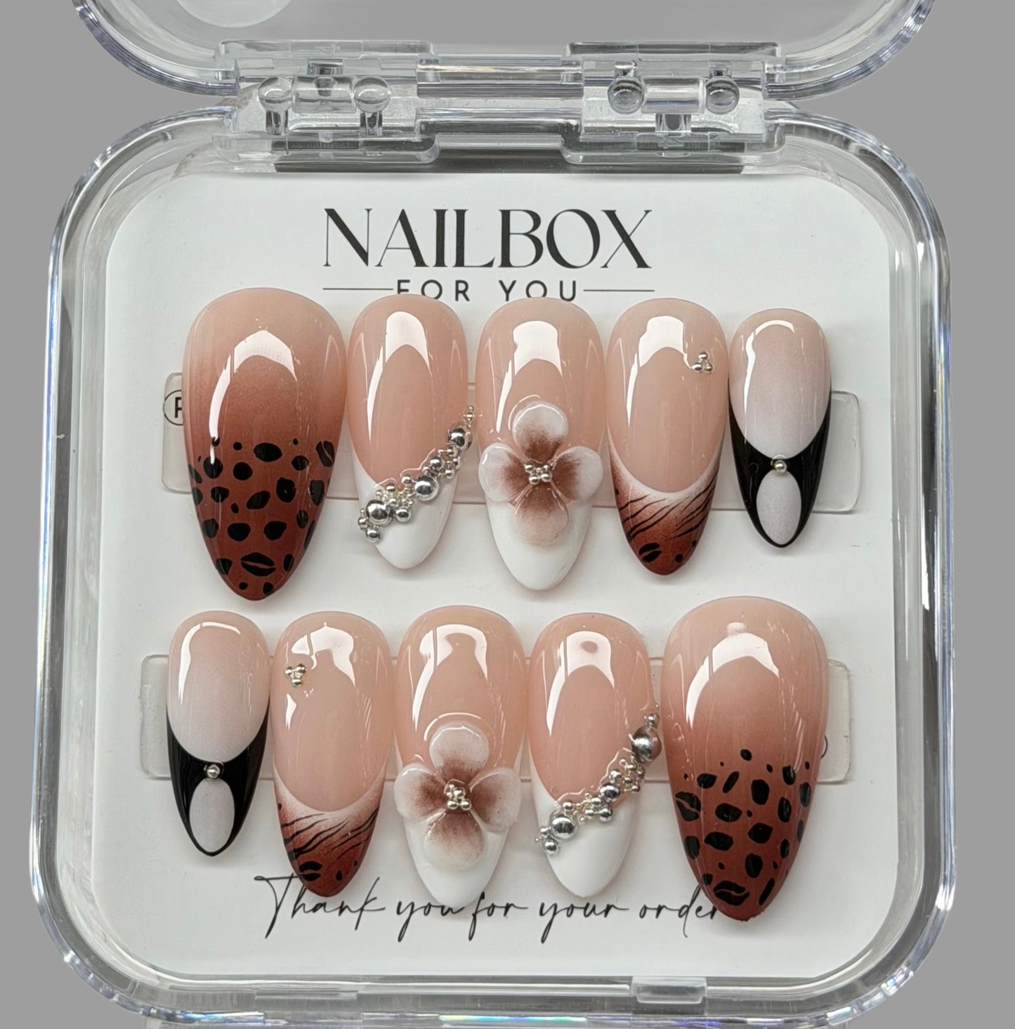 Nail art display with various designs in a clear box labeled 'NAILBOX FOR YOU'.