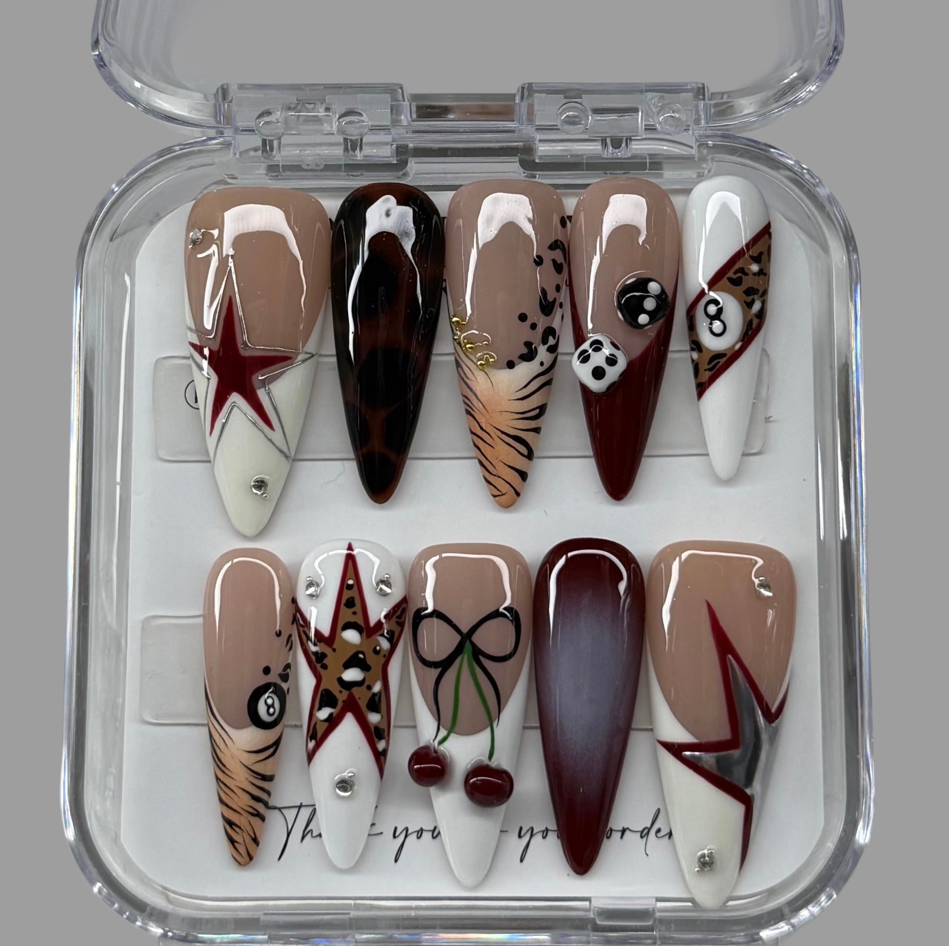 Set of nail art designs in a clear case on a gray background